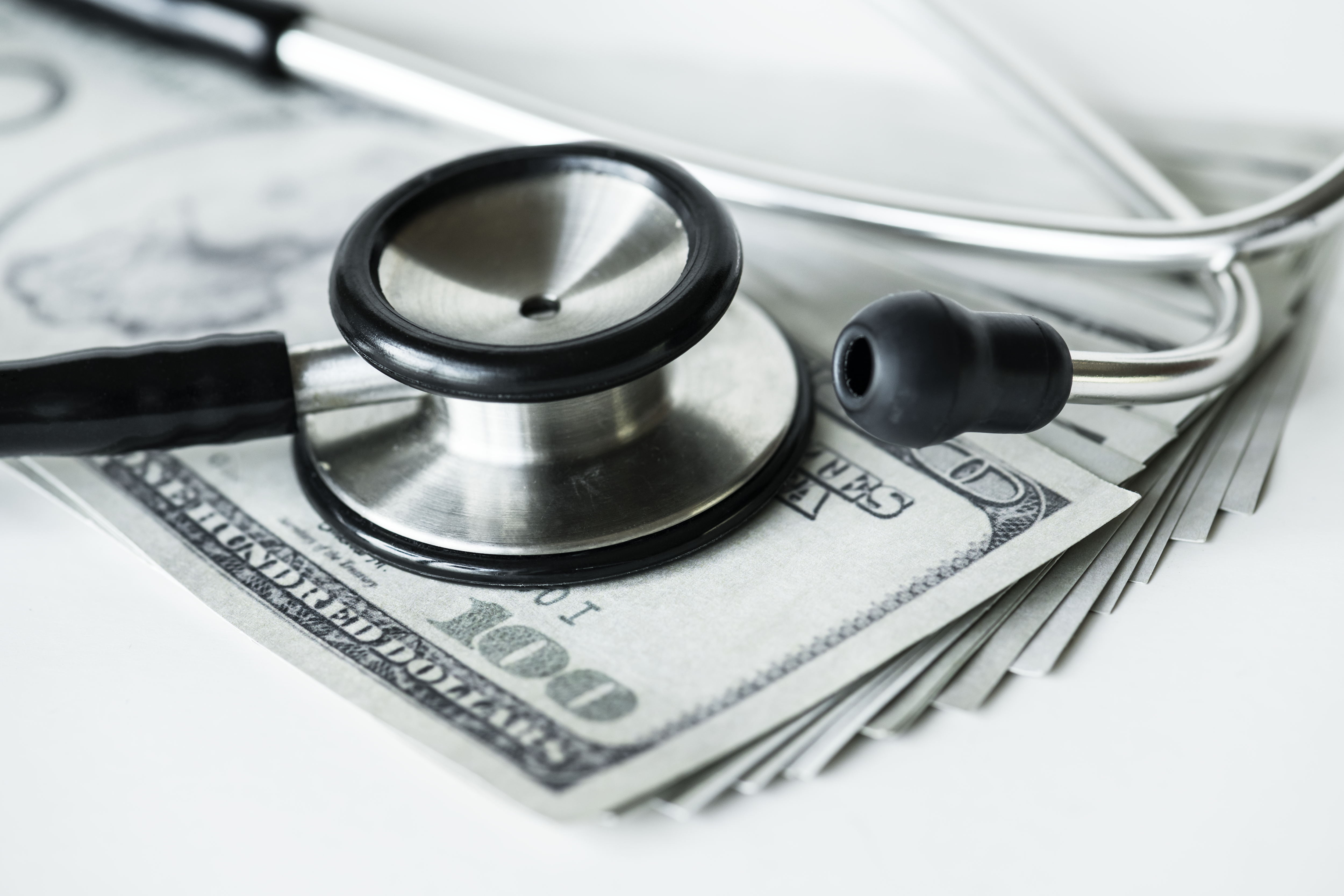 Closeup of cash and a stethoscope healthcare and expenses concep